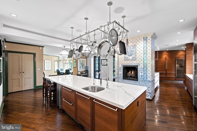 kitchen featuring dark wood-style flooring, a spacious island, recessed lighting, a large fireplace, and a sink