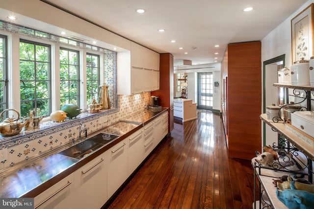 kitchen with recessed lighting, dark wood-type flooring, a sink, white cabinets, and backsplash