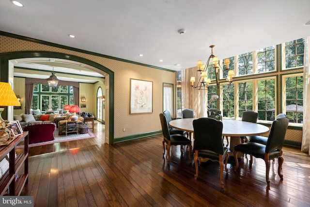 dining room with arched walkways, wallpapered walls, ornamental molding, a chandelier, and hardwood / wood-style flooring