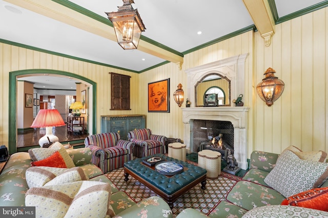 living area with beam ceiling, a fireplace, arched walkways, and crown molding