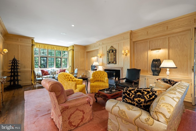 living room featuring crown molding, dark wood-style flooring, a decorative wall, and a lit fireplace