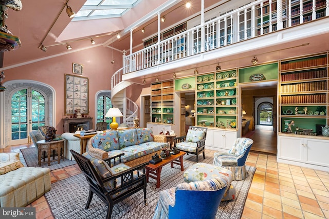 living room with arched walkways, high vaulted ceiling, a skylight, a fireplace, and track lighting