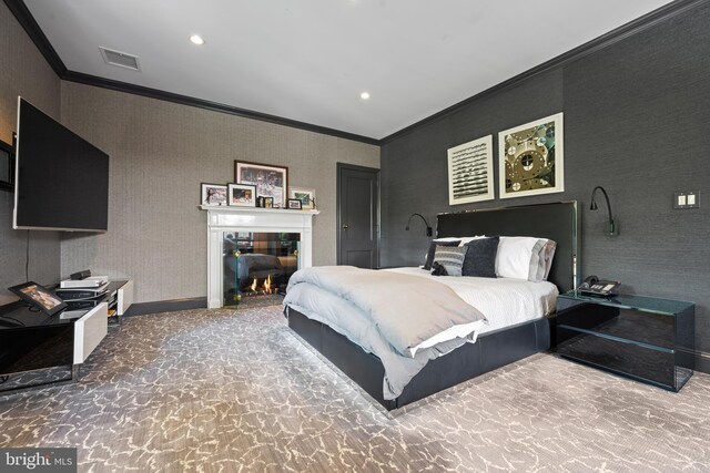 carpeted bedroom with wallpapered walls, baseboards, visible vents, a tile fireplace, and crown molding