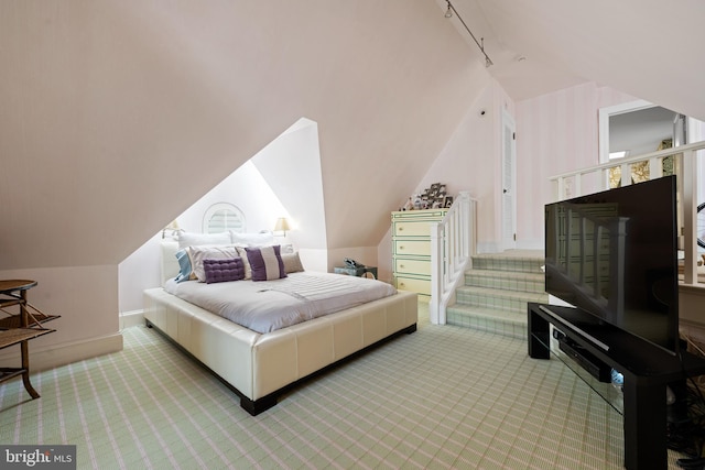 bedroom featuring carpet, rail lighting, lofted ceiling, and baseboards