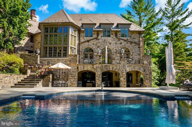 outdoor pool with stairway and a patio area