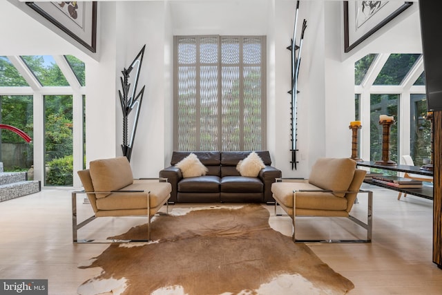 living room featuring a sunroom, a high ceiling, and wood finished floors