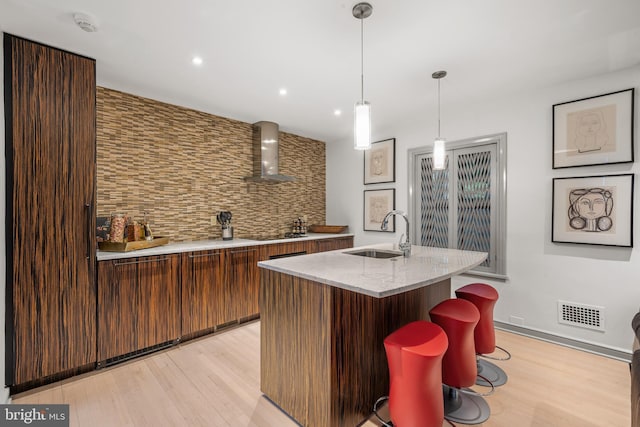 bar featuring black electric cooktop, a sink, visible vents, light wood-type flooring, and wall chimney exhaust hood