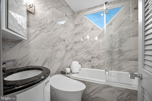 full bath featuring marble finish floor, tile walls, toilet, tiled shower / bath combo, and vanity