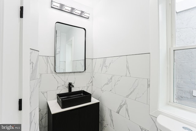 half bath with toilet, vanity, and tile walls