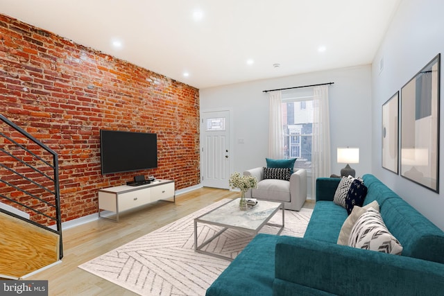 living area with recessed lighting, baseboards, brick wall, and wood finished floors