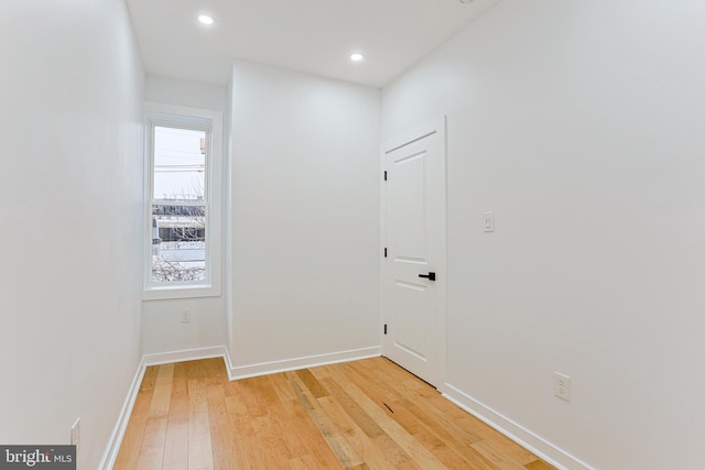 corridor featuring recessed lighting, light wood-type flooring, a wealth of natural light, and baseboards