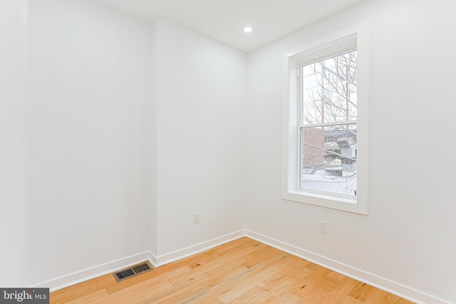 empty room featuring light wood-type flooring, baseboards, visible vents, and a wealth of natural light