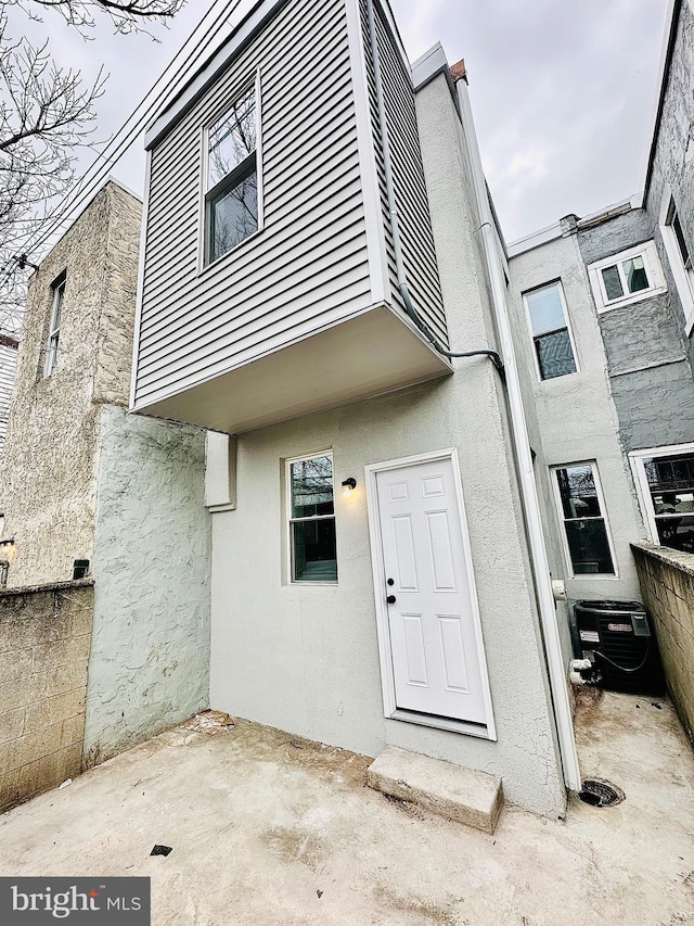 rear view of house featuring cooling unit, a patio, and stucco siding