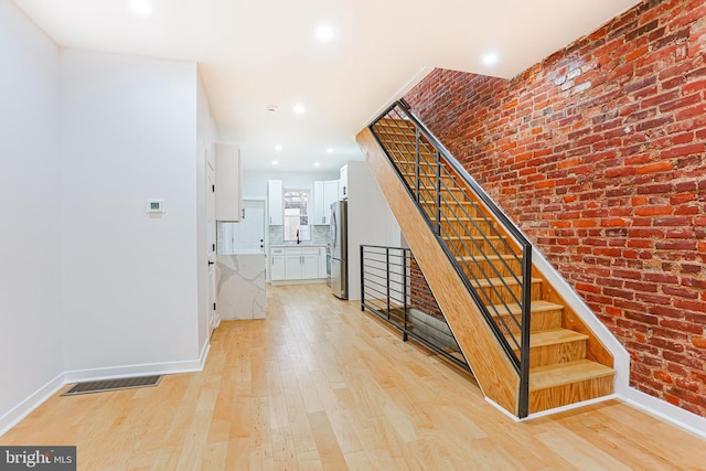 stairway featuring recessed lighting, visible vents, brick wall, wood finished floors, and baseboards