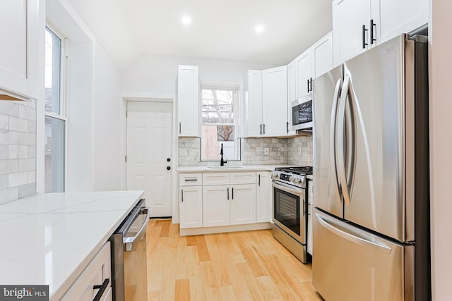 kitchen featuring stainless steel appliances, light wood-style floors, white cabinetry, and a sink