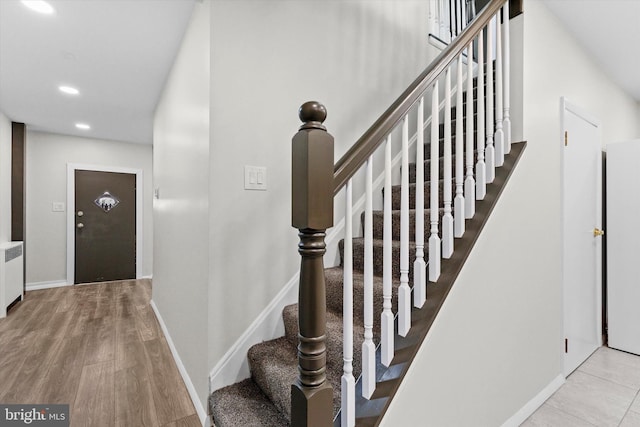 stairway featuring radiator heating unit, baseboards, wood finished floors, and recessed lighting