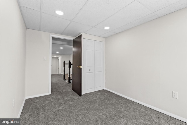 spare room with recessed lighting, a drop ceiling, dark carpet, and baseboards