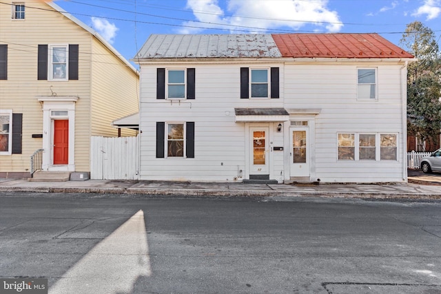 view of front of property featuring metal roof and fence