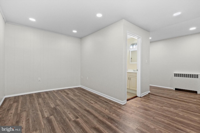 interior space with radiator, wood finished floors, and recessed lighting