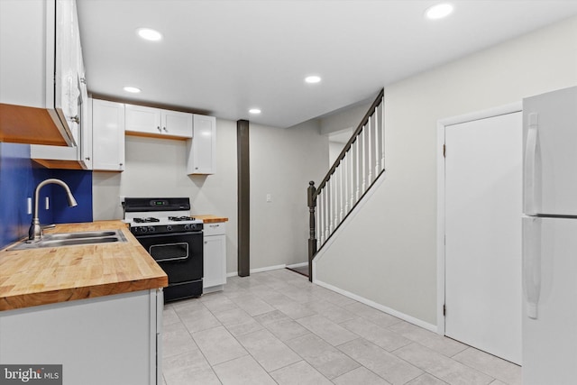 kitchen featuring range with gas cooktop, freestanding refrigerator, white cabinetry, wooden counters, and a sink