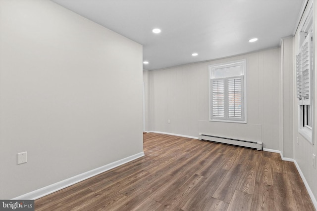 empty room with a baseboard heating unit, recessed lighting, wood finished floors, and baseboards