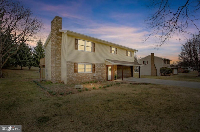 traditional home featuring brick siding, concrete driveway, a lawn, a chimney, and a garage