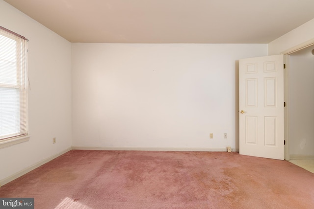 carpeted empty room featuring baseboards