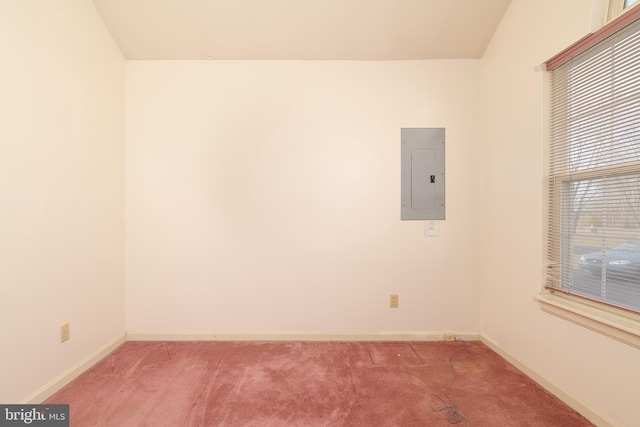 spare room with electric panel, baseboards, and light carpet