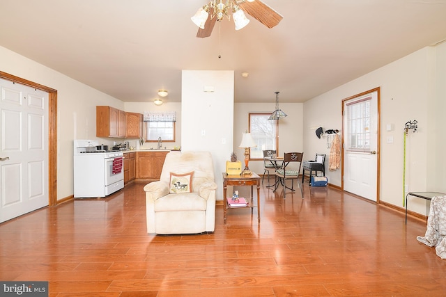 living room with light wood finished floors, baseboards, and ceiling fan