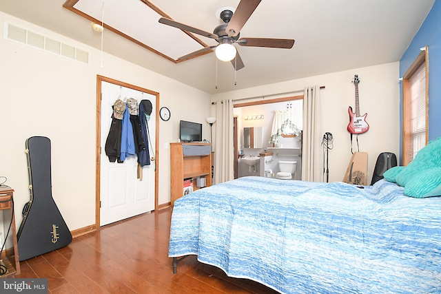 bedroom featuring a ceiling fan, wood finished floors, visible vents, baseboards, and ensuite bathroom