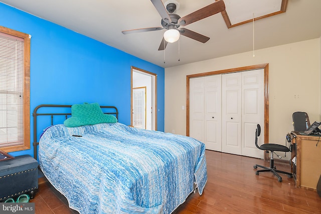 bedroom with a closet, attic access, wood finished floors, and a ceiling fan