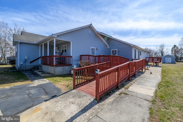 view of side of property with a deck, a shingled roof, and a yard