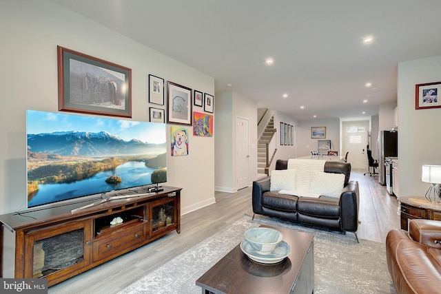 living area with light wood-type flooring, baseboards, stairway, and recessed lighting