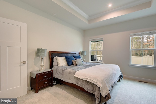 bedroom featuring visible vents, a raised ceiling, multiple windows, and light carpet