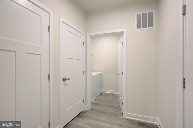 hall with baseboards, washer and clothes dryer, visible vents, and light wood-style floors