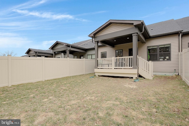 back of property featuring a yard and fence