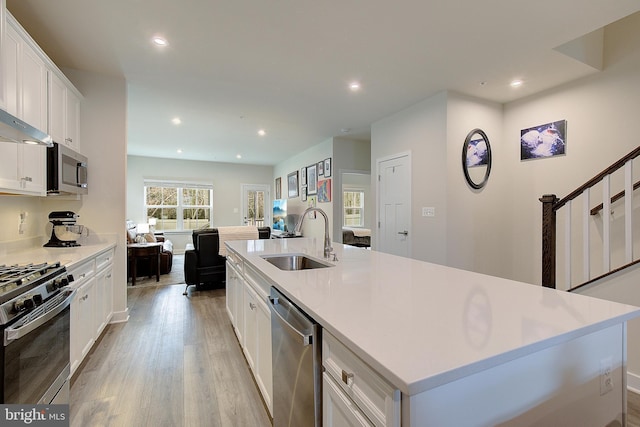 kitchen featuring light wood-style flooring, recessed lighting, a sink, white cabinets, and appliances with stainless steel finishes