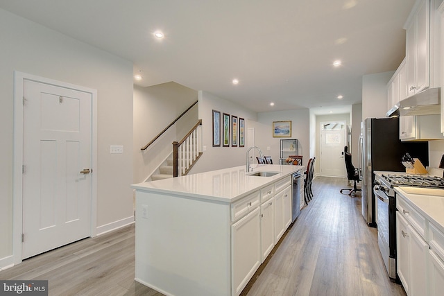 kitchen with under cabinet range hood, a sink, stainless steel dishwasher, an island with sink, and gas stove