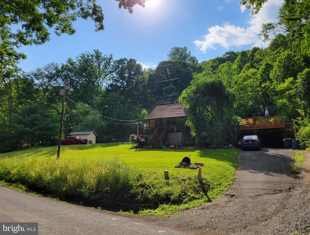 view of front of property with stairs, a front yard, driveway, and a wooden deck