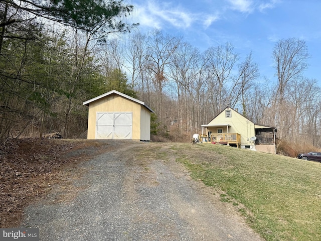 exterior space featuring gravel driveway, an outbuilding, a lawn, and a garage