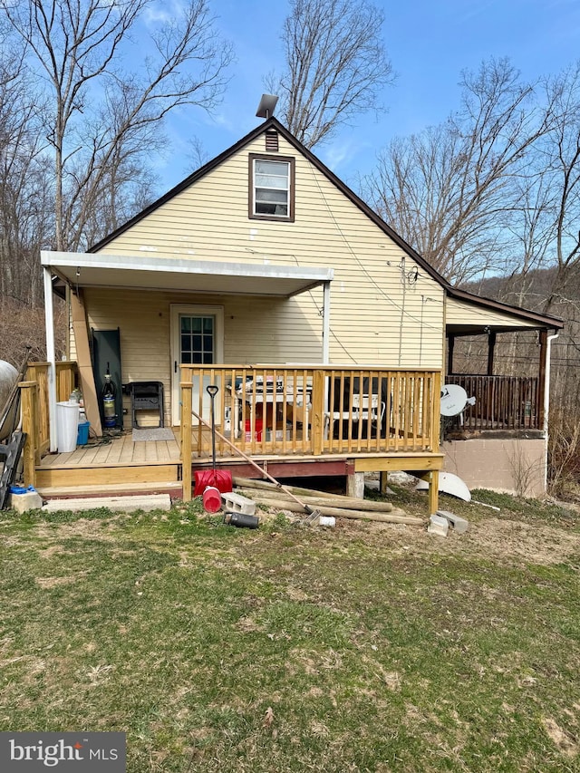 rear view of property featuring a lawn and a wooden deck