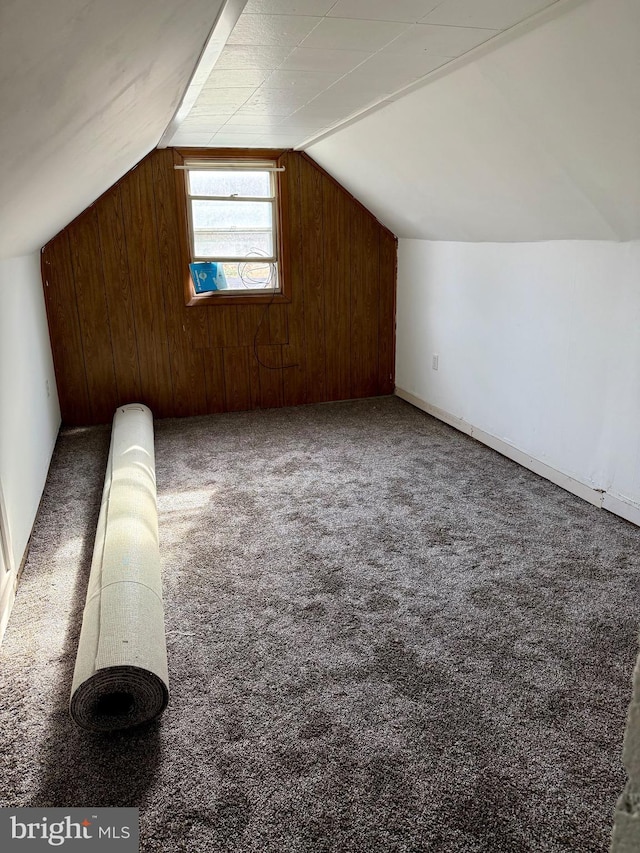 bonus room with vaulted ceiling, wood walls, and carpet floors