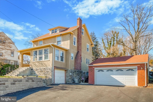 traditional style home featuring stone siding, a chimney, central AC, and stucco siding