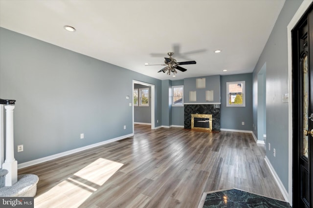 unfurnished living room with ceiling fan, recessed lighting, a premium fireplace, wood finished floors, and baseboards