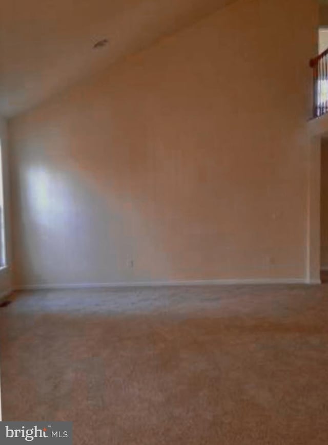 carpeted empty room with baseboards and high vaulted ceiling