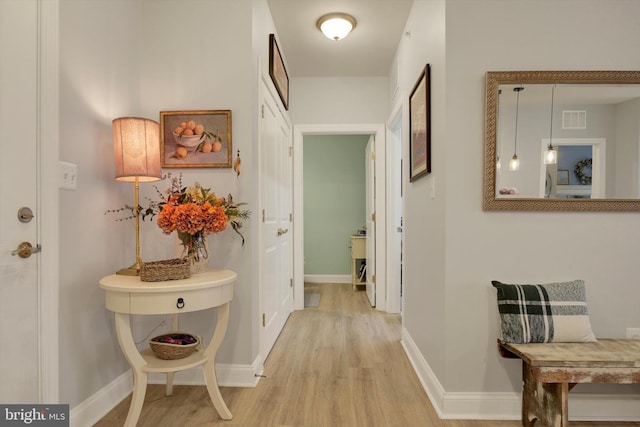 corridor featuring light wood-type flooring, baseboards, and visible vents