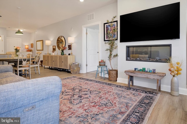 living room with wood finished floors, visible vents, and baseboards