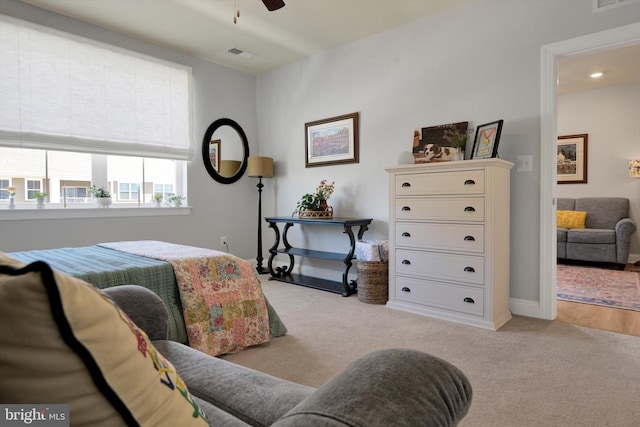 bedroom with baseboards, visible vents, and light colored carpet