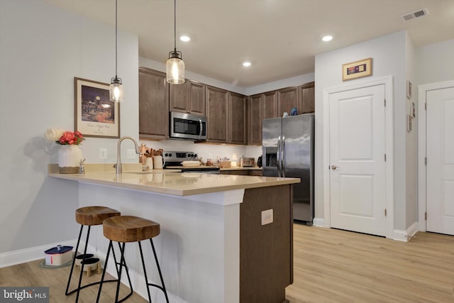 kitchen featuring stainless steel appliances, a peninsula, visible vents, and a kitchen breakfast bar