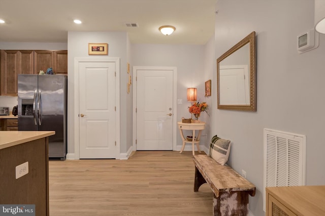 kitchen featuring stainless steel fridge, visible vents, light countertops, and light wood-style flooring